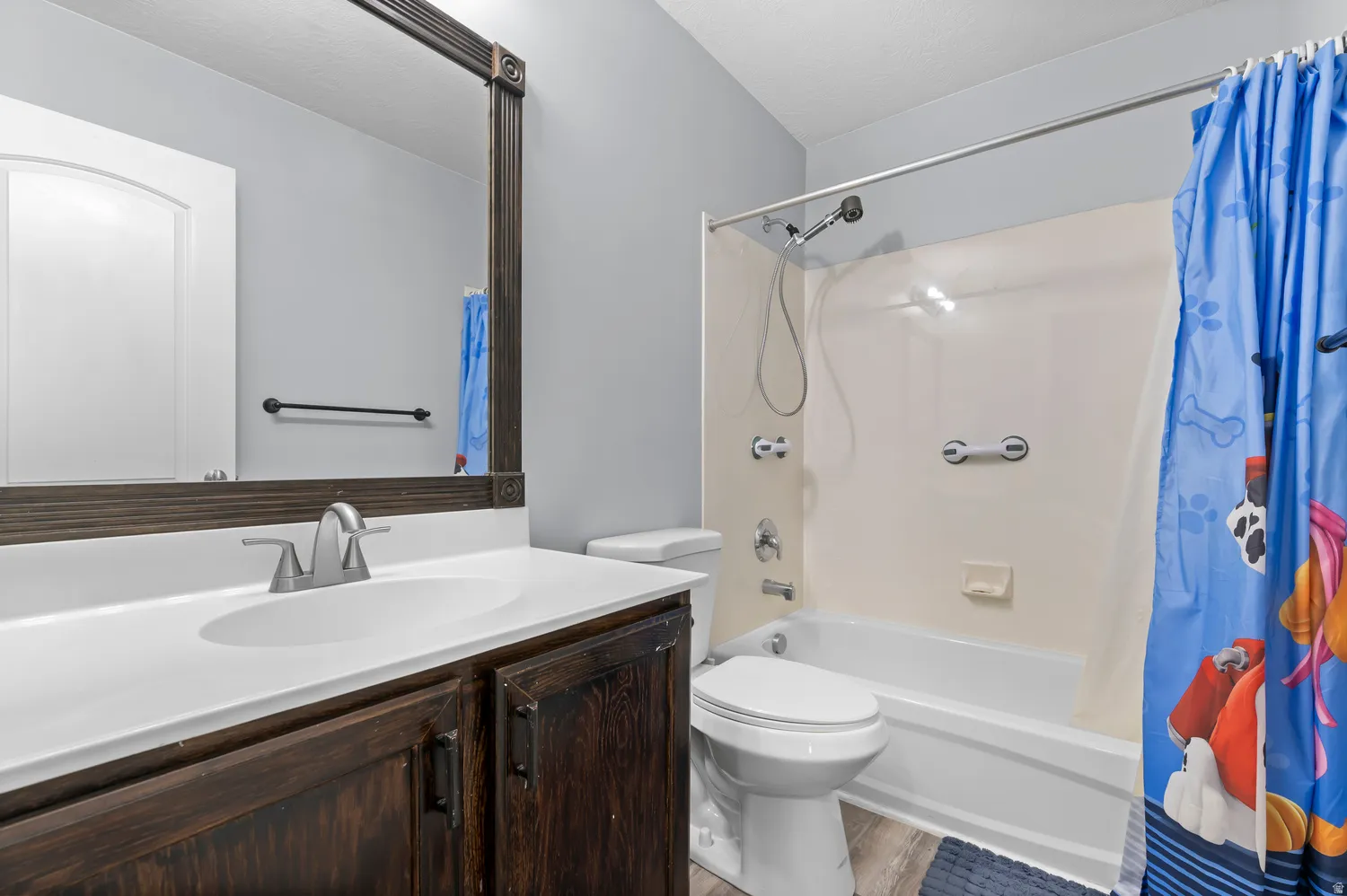 Bathroom featuring a dark wood-finish vanity with a white countertop and undermount sink, brushed nickel faucet, and a large mirror with an ornate frame