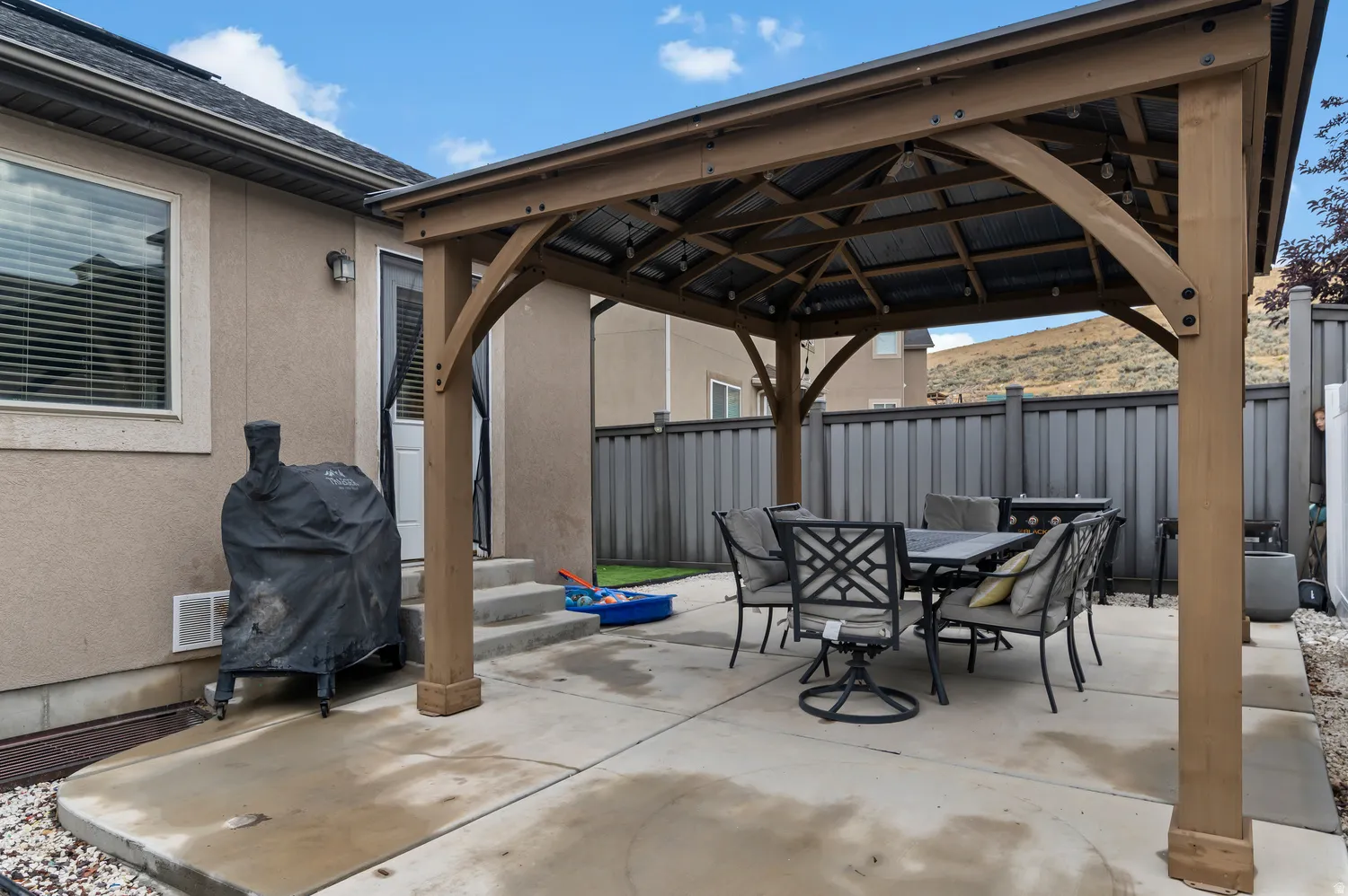 Patio featuring a permanent gazebo with a metal roof, concrete surface, and privacy fencing