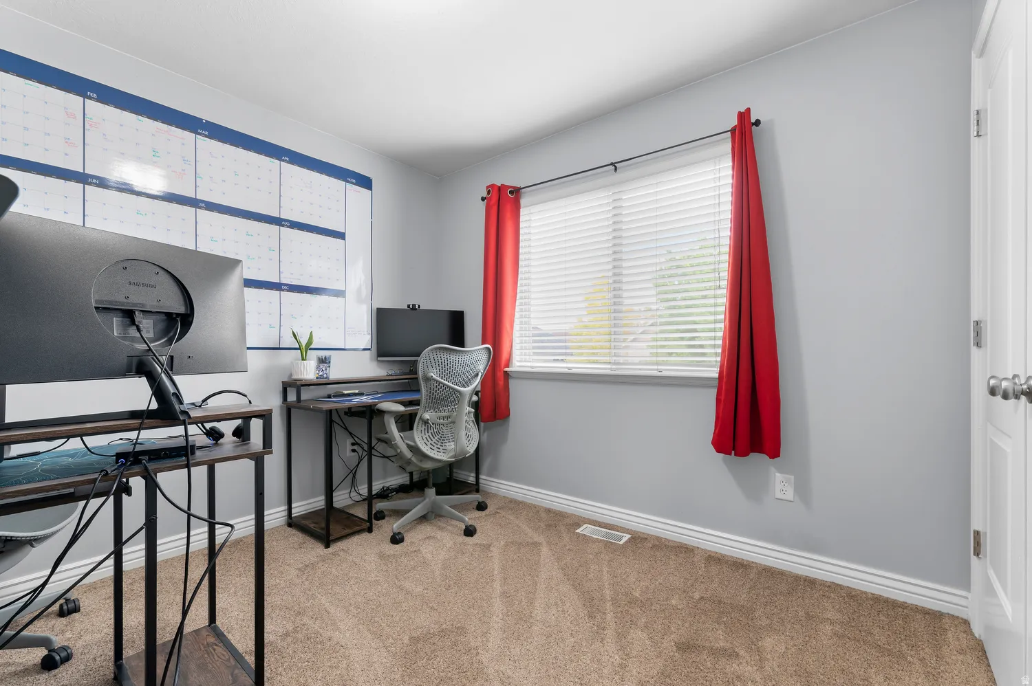 Light gray wall paint, brown carpet flooring, and a window with horizontal blinds
