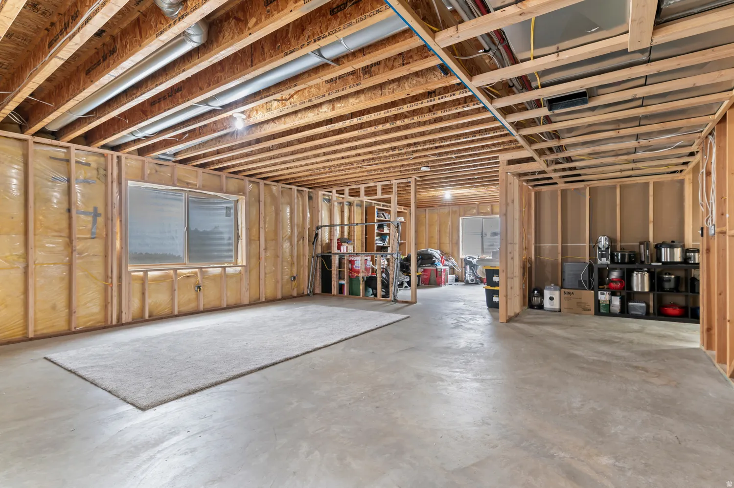Unfinished lower level featuring concrete flooring, exposed wood joists, and structural framing
