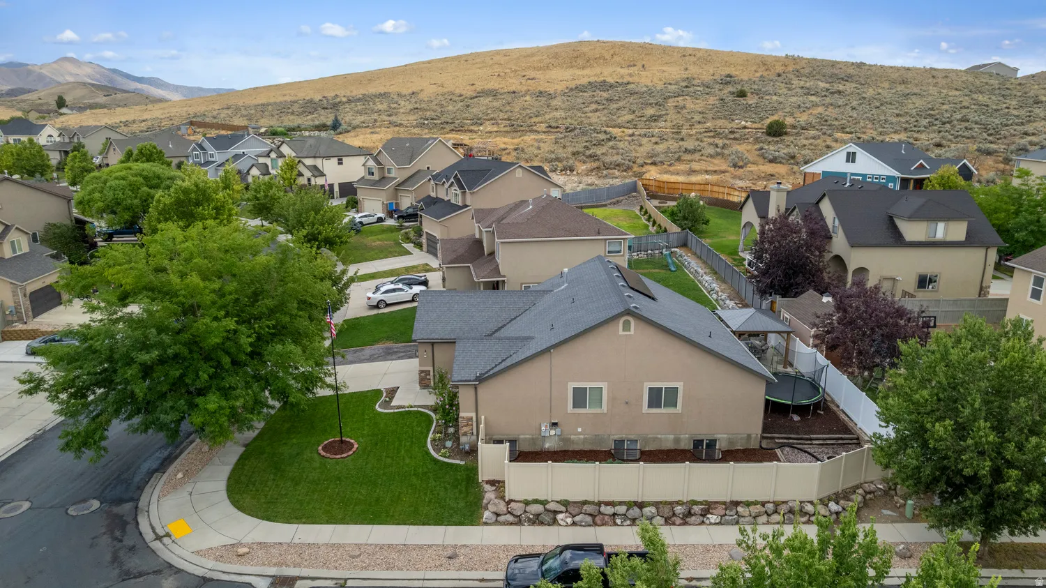 Residential neighborhood with varied architectural styles and mature landscaping, featuring a paved street and concrete sidewalks