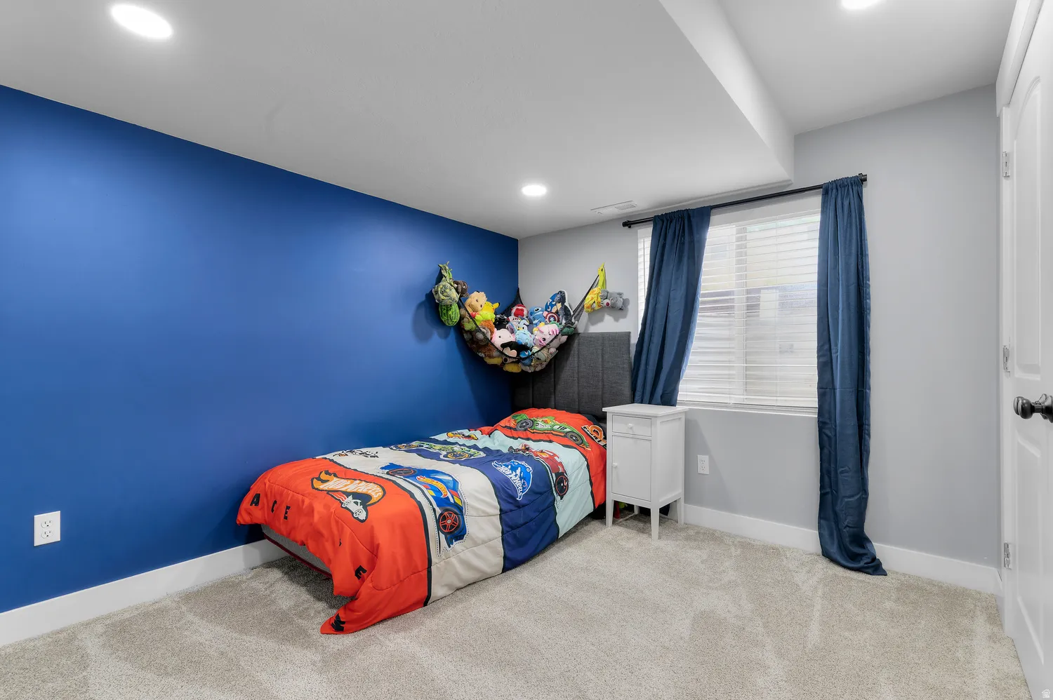 Recessed ceiling lighting illuminates a room with a window featuring horizontal blinds