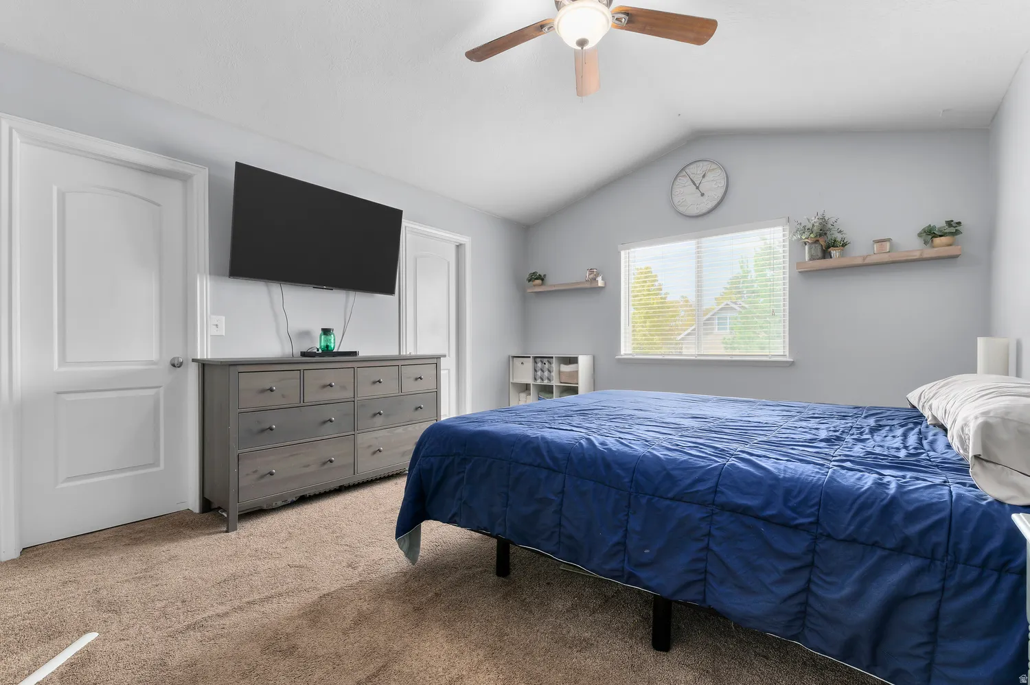 Vaulted ceiling with an attached ceiling fan, dual doors, and a window with blinds