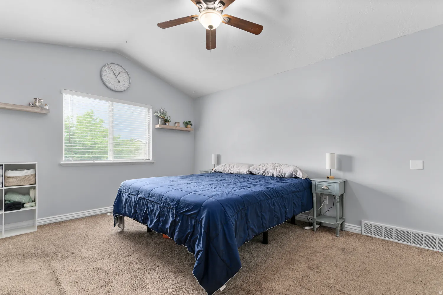Angled ceiling with a ceiling fan, window with blinds, and wall-mounted shelving