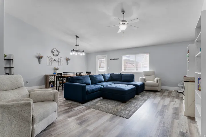 Vaulted ceiling, wood-finish flooring, ceiling fan, contemporary dining chandelier, and built-in shelving