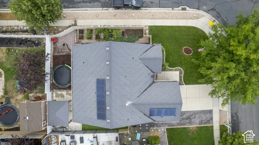 Gable roofline with solar panel arrays, expansive front yard with manicured lawn, concrete driveway, and established perimeter landscaping