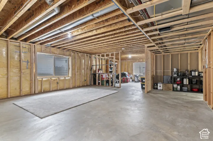 Unfinished lower level featuring concrete flooring, exposed wood joists, and structural framing