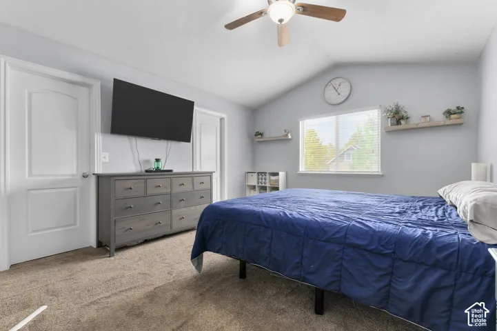 Vaulted ceiling with an attached ceiling fan, dual doors, and a window with blinds