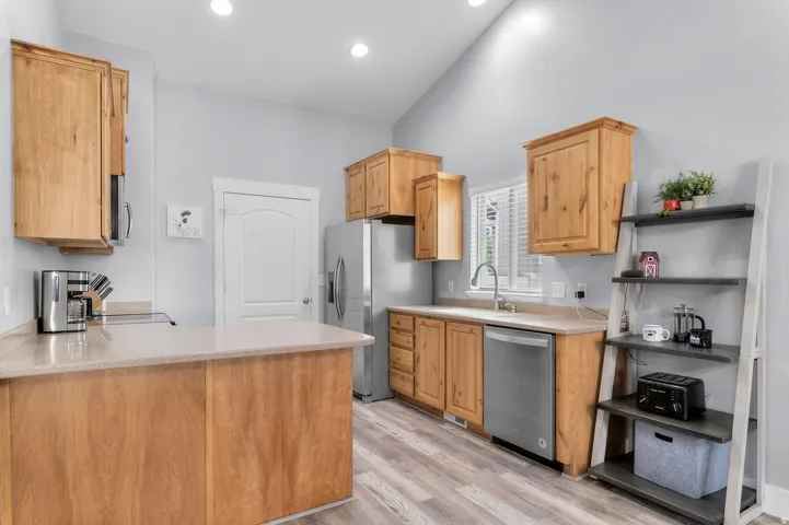 Kitchen featuring wood cabinetry, stainless steel appliances, light-toned countertops, and wood-finish flooring
