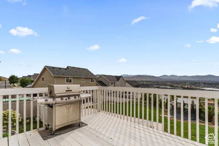 Outdoor deck with white railing, wood-finish flooring, and distant mountain scenery
