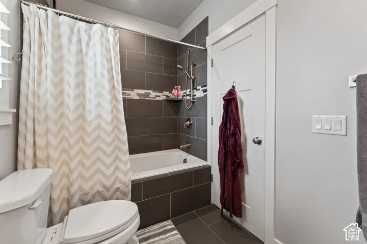Bathtub with dark tile surround, integrated shower head, and a recessed shelf