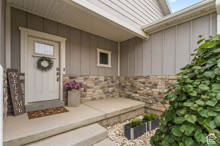 Inviting front entrance featuring a panel-paneled entry door with transom window, concrete steps, a covered porch, and a stone veneer foundation