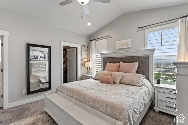 Vaulted ceiling with a ceiling fan, tufted headboard, white trim, and a built-in closet with double doors