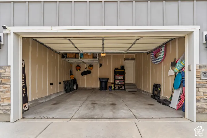 Attached two-car garage with concrete flooring, overhead lighting, and built-in shelving
