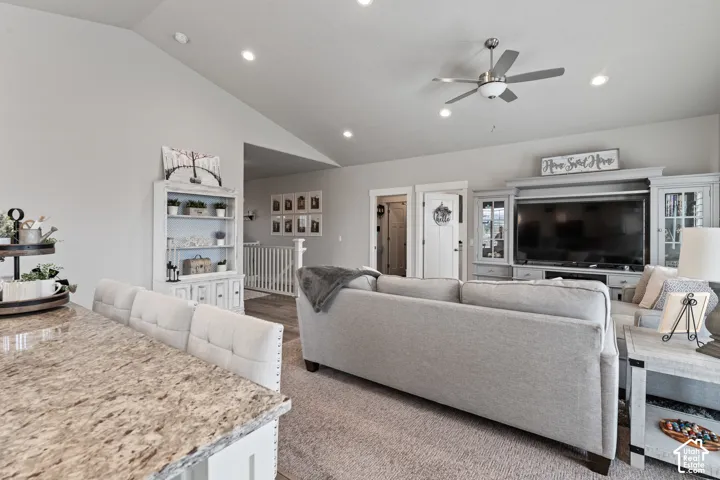 Vaulted ceiling with recessed lighting, granite countertop, built-in entertainment center, ceiling fan, and wood-finish flooring