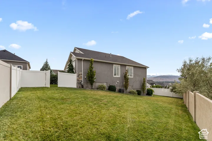 Expansive green lawn with a white privacy fence and a stucco-clad exterior featuring multiple windows