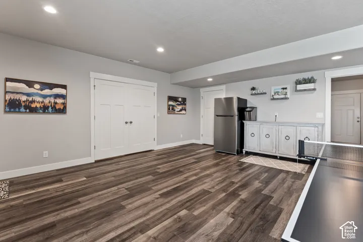Wood-finish flooring throughout, recessed lighting, double doors, built-in cabinetry, and a stainless steel refrigerator