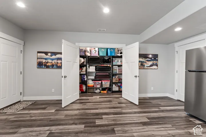 Wood-finish flooring, recessed lighting, white trim, and a built-in closet with shelving