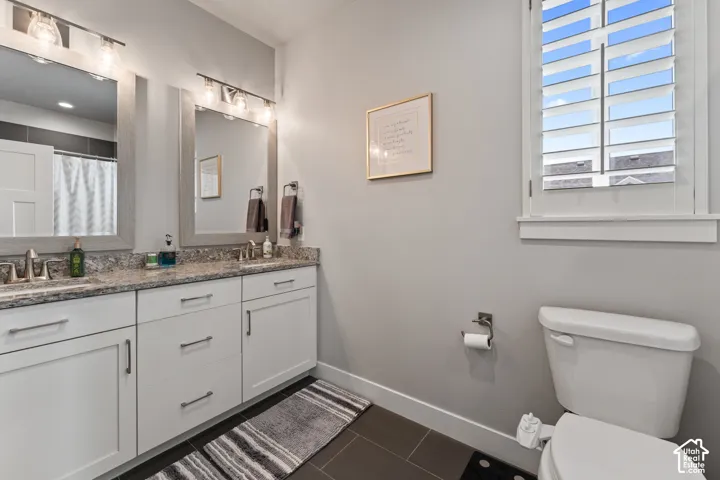 Double vanity with granite countertops, integrated sinks, white cabinetry, and brushed nickel hardware