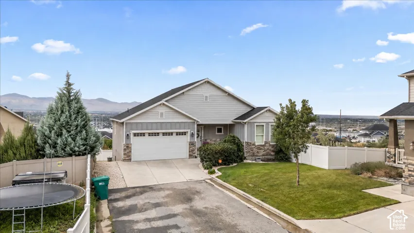 Charming single-story residence featuring a clean stucco exterior, two-car garage with paneled doors, and a manicured front lawn with mature landscaping