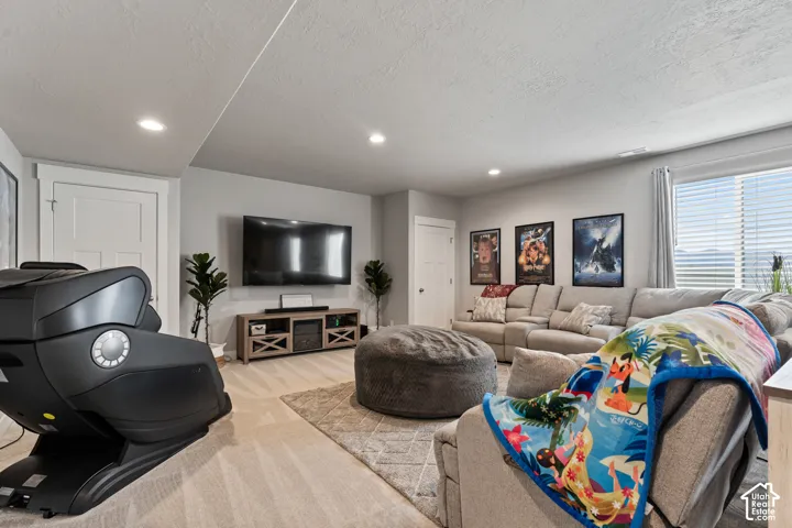 Recessed lighting, wood-finish flooring, light grey wall paint, and a built-in media console