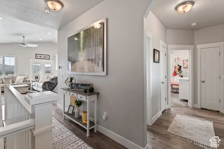 Vaulted ceiling, recessed lighting, wood-finish flooring, white door casings, and a white stair railing