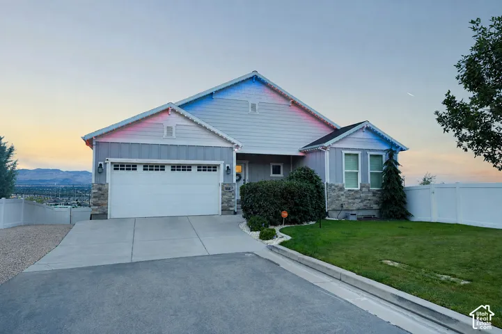 Siding exterior with stone accents, attached garage, concrete driveway, and manicured lawn