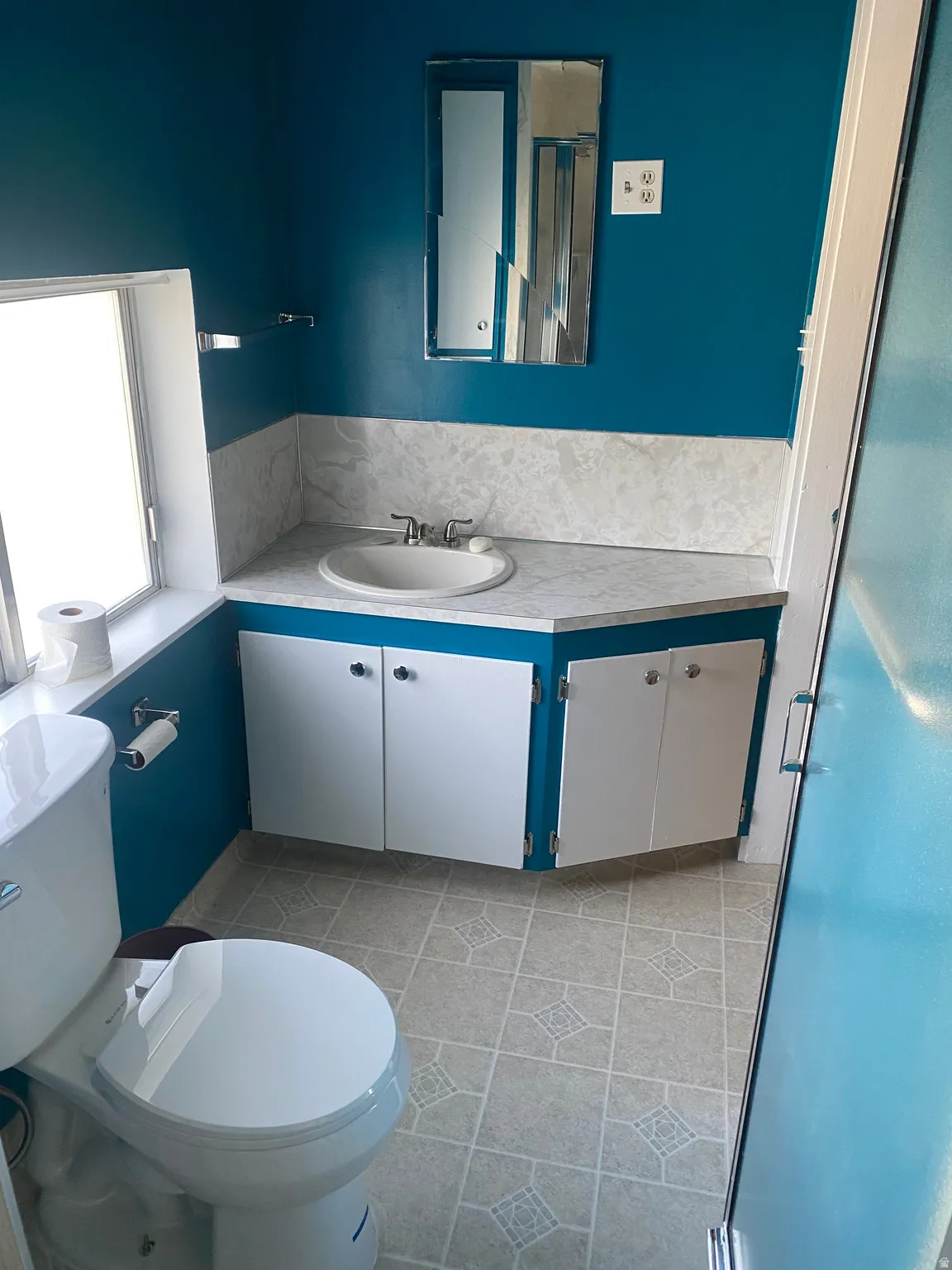Bathroom featuring a corner vanity with an integrated sink, white cabinetry, and patterned flooring