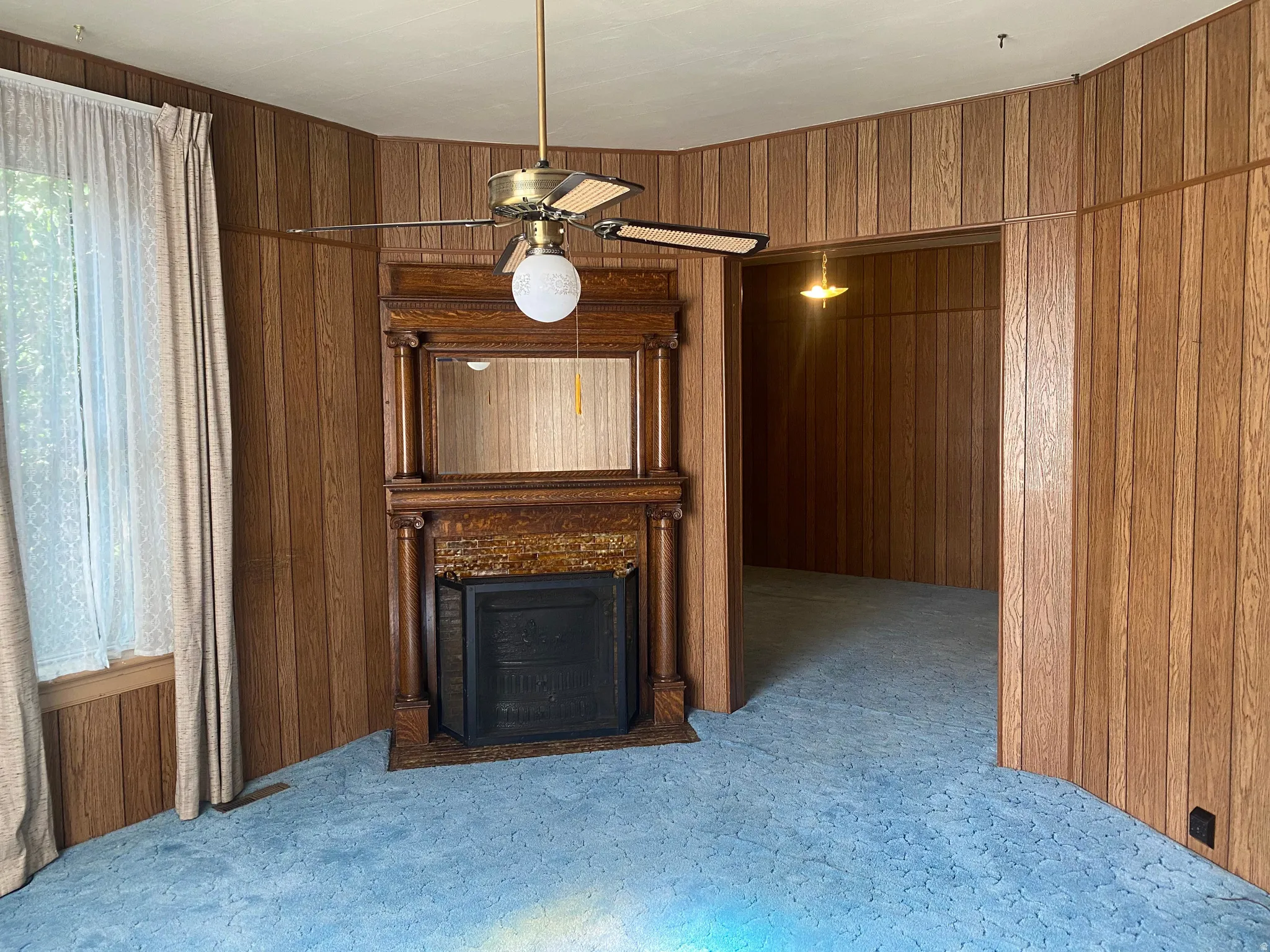 Wood-paneled room with a classic fireplace, ornate wood mantel, and built-in mirror