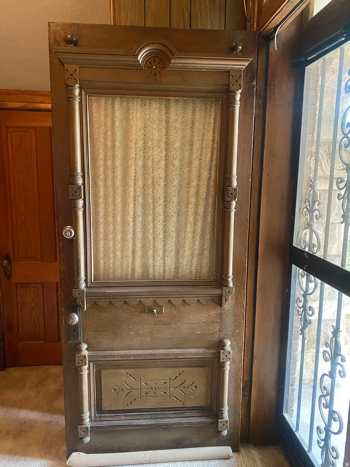 Ornate wood-paneled door with detailed carvings and a central glass panel