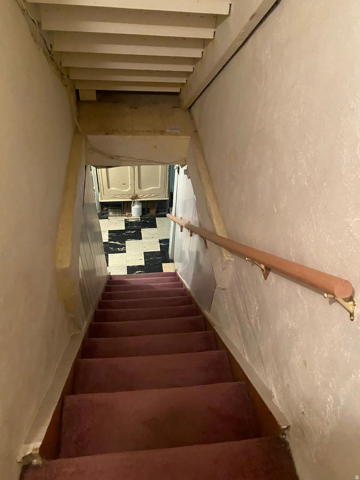 Stairway featuring a wood handrail, textured walls, and carpeted treads