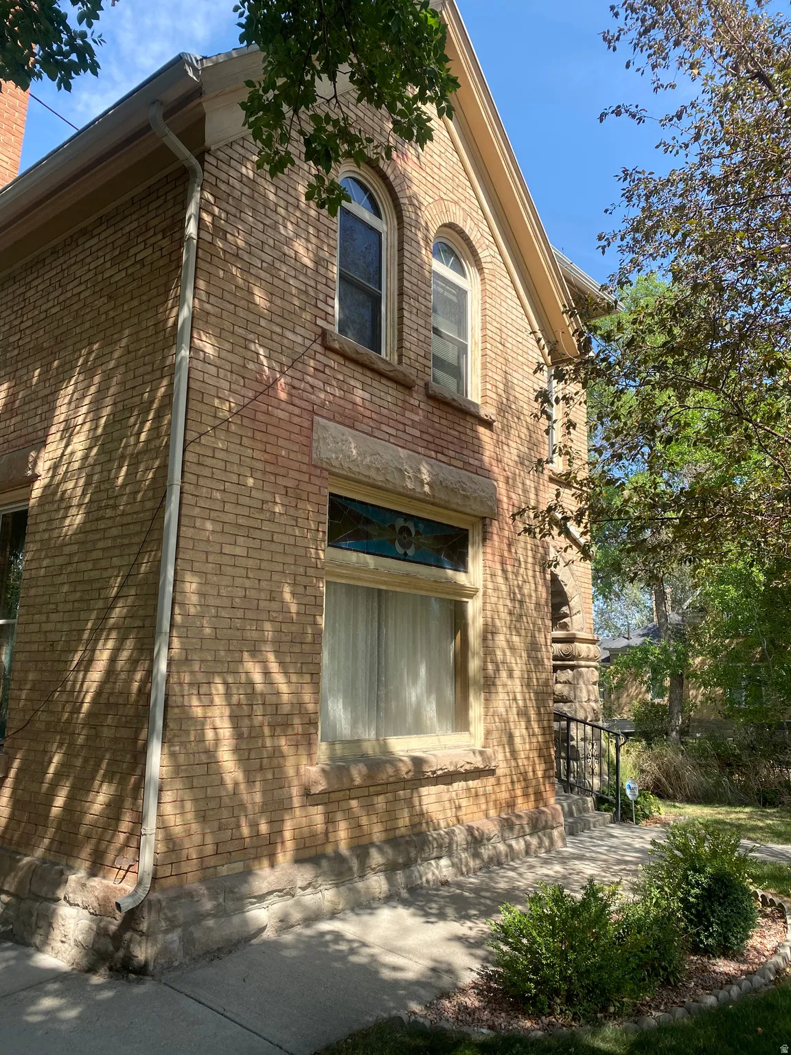 Brick exterior with arched windows, stone detailing, and a decorative stained-glass transom