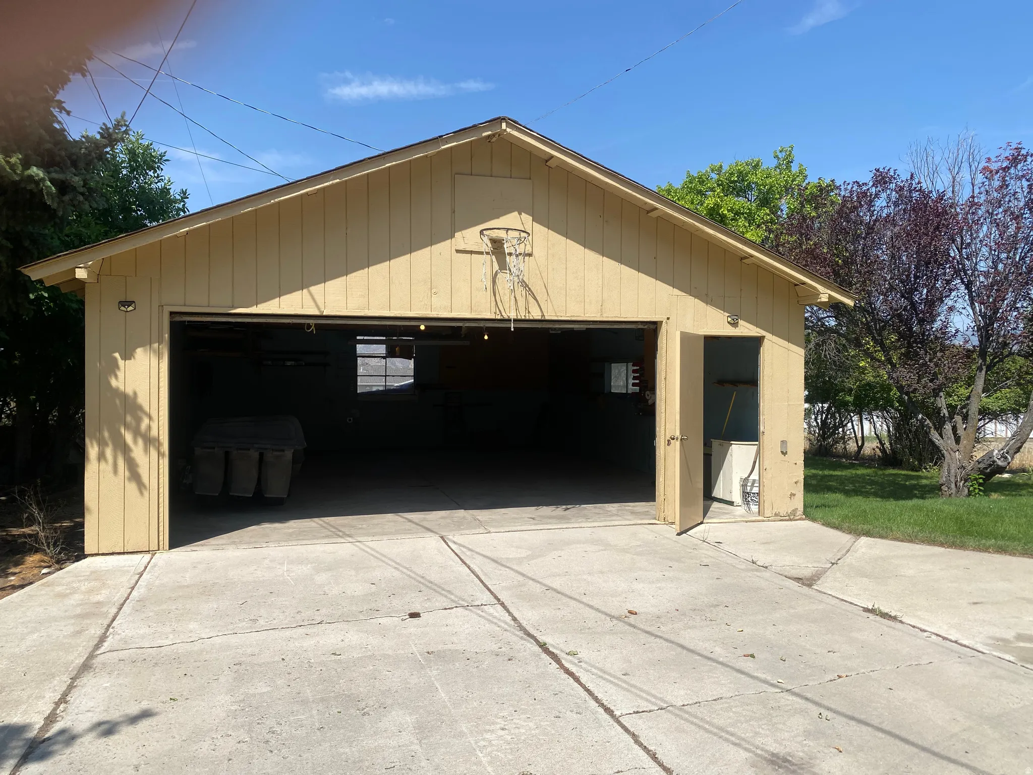 Detached garage with a gable roof, light-colored siding, and a concrete driveway