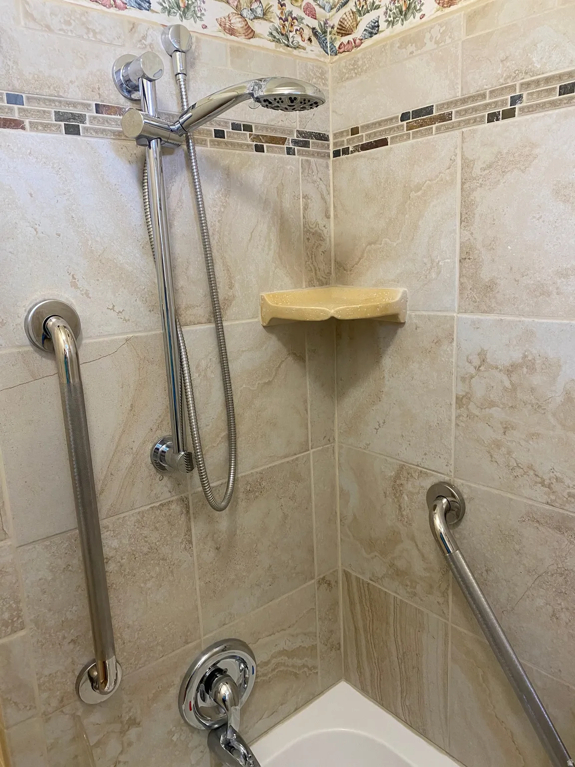 Tile shower surround with an integrated mosaic accent band and decorative border