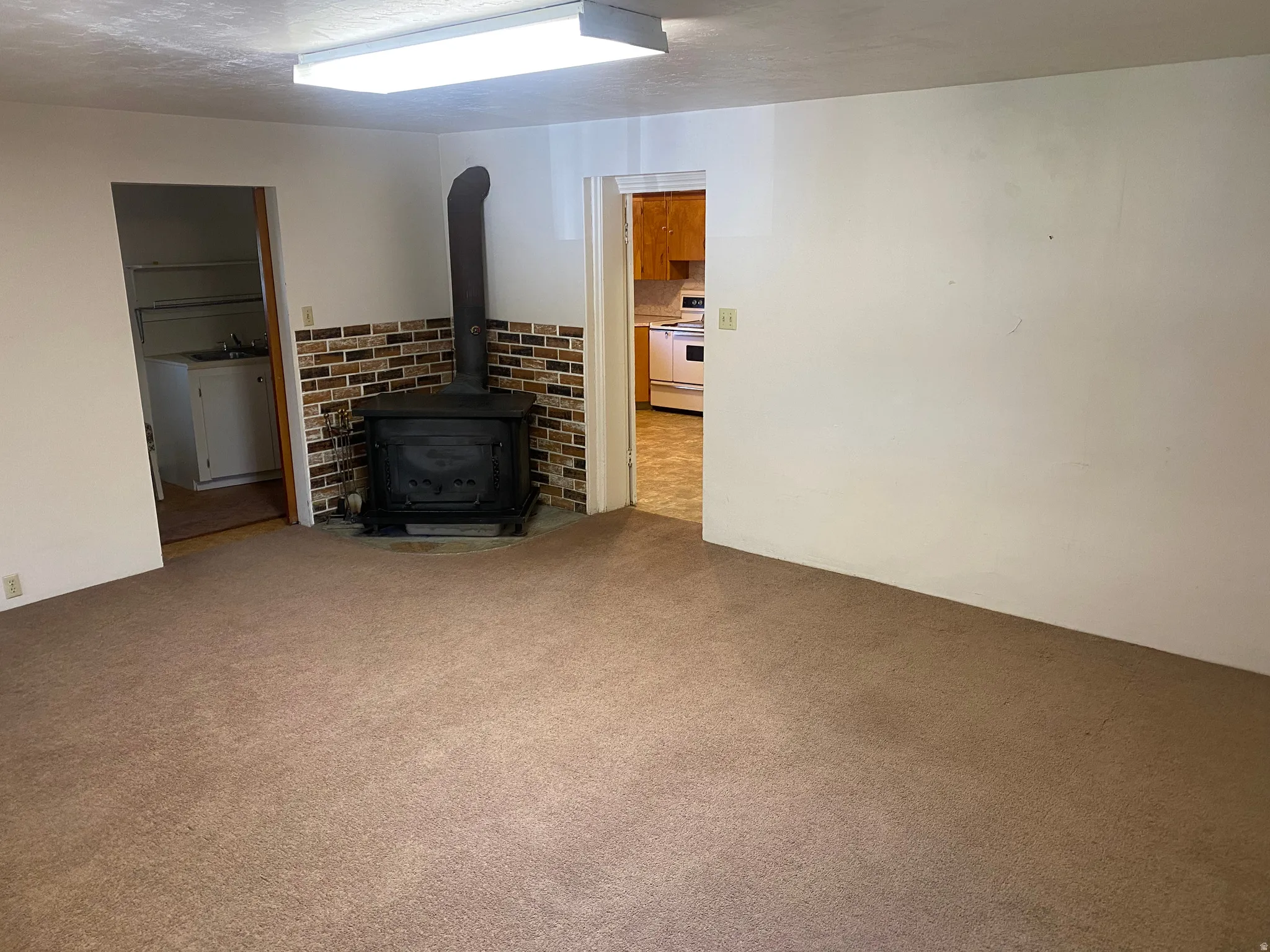 Integrated wood-burning stove with a brick-patterned surround, carpet flooring, and white walls