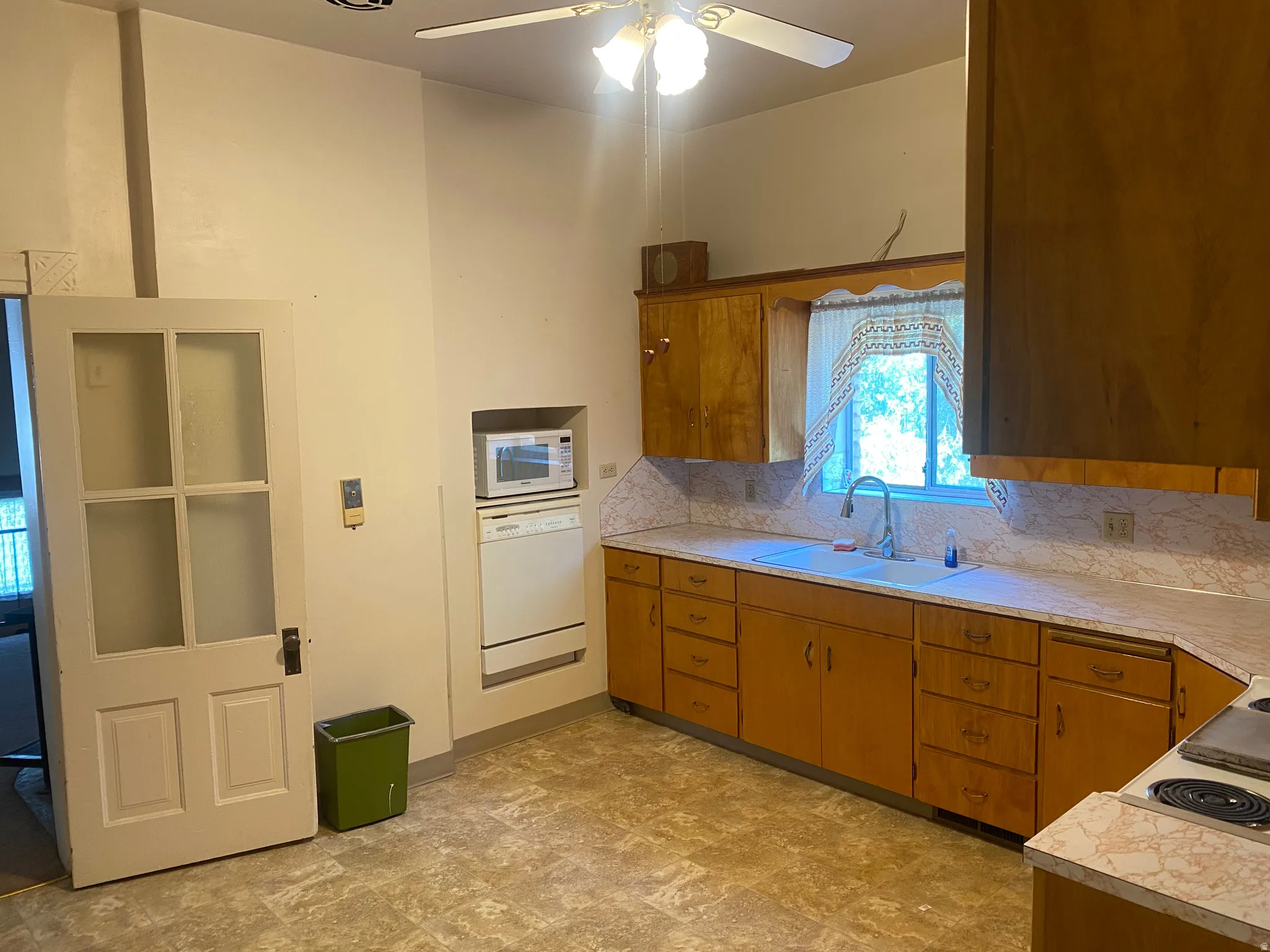 Kitchen featuring a window, built-in cabinetry, a ceiling fan, and a built-in appliance niche