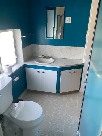 Bathroom featuring a corner vanity with an integrated sink, white cabinetry, and patterned flooring