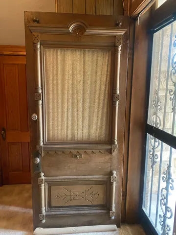 Ornate wood-paneled door with detailed carvings and a central glass panel