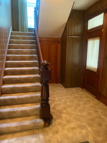 Staircase featuring a wood banister and carpeted treads