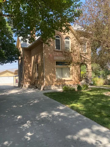 Brick exterior with arched windows, gabled roofline, and established landscaping