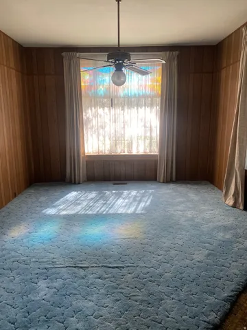Wood-paneled walls with a central window, featuring a ceiling fan with light fixture