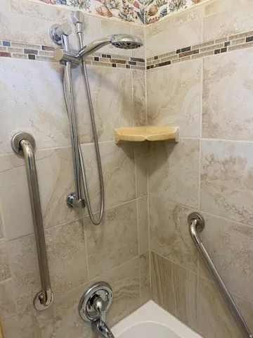 Tile shower surround with an integrated mosaic accent band and decorative border