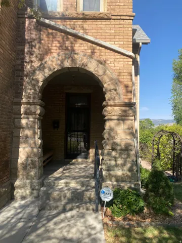 Brick exterior with a stone-clad entry archway, stone steps, and a wrought iron railing