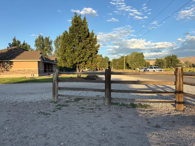 Split rail fence, gravel driveway, stucco and stone exterior, covered front porch, mature trees