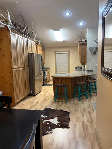 Kitchen featuring light wood-finish flooring, recessed lighting, wood cabinetry, and a peninsula with a built-in breakfast bar