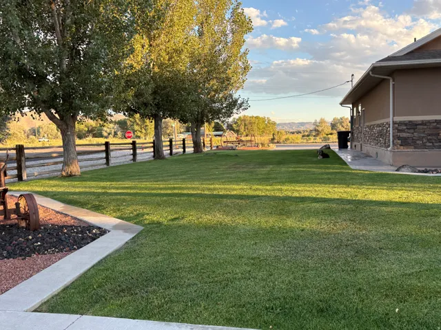 Expansive lawn featuring mature trees and a wood-post fence