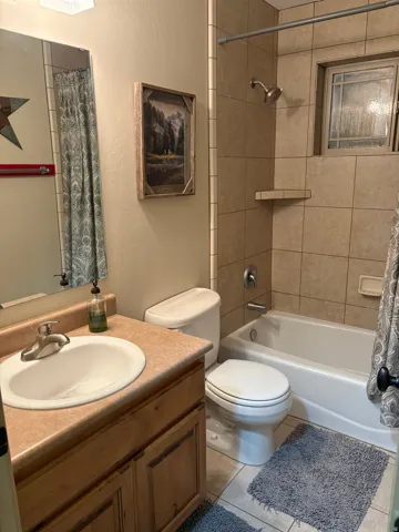 Bathroom featuring a built-in vanity with an integrated sink, a full bathtub, and tiled shower surround with an accent window
