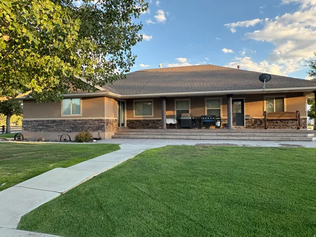 Stucco exterior with stone veneer accents, covered front porch, and a shingle roof