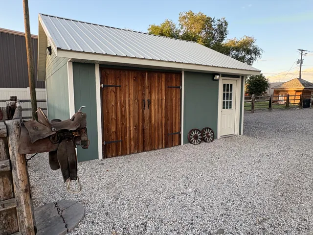 Detached structure featuring board-and-batten siding, a metal roof, and large wood-paneled doors