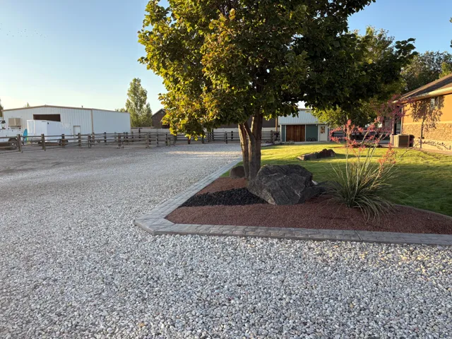 Expansive gravel driveway bordered by concrete pavers